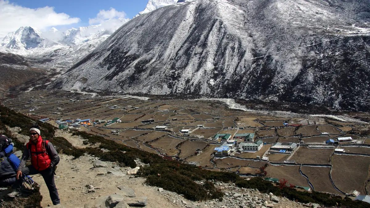 Trekker oberhalb von Dingboche mit den Steinmauern des Dorfes