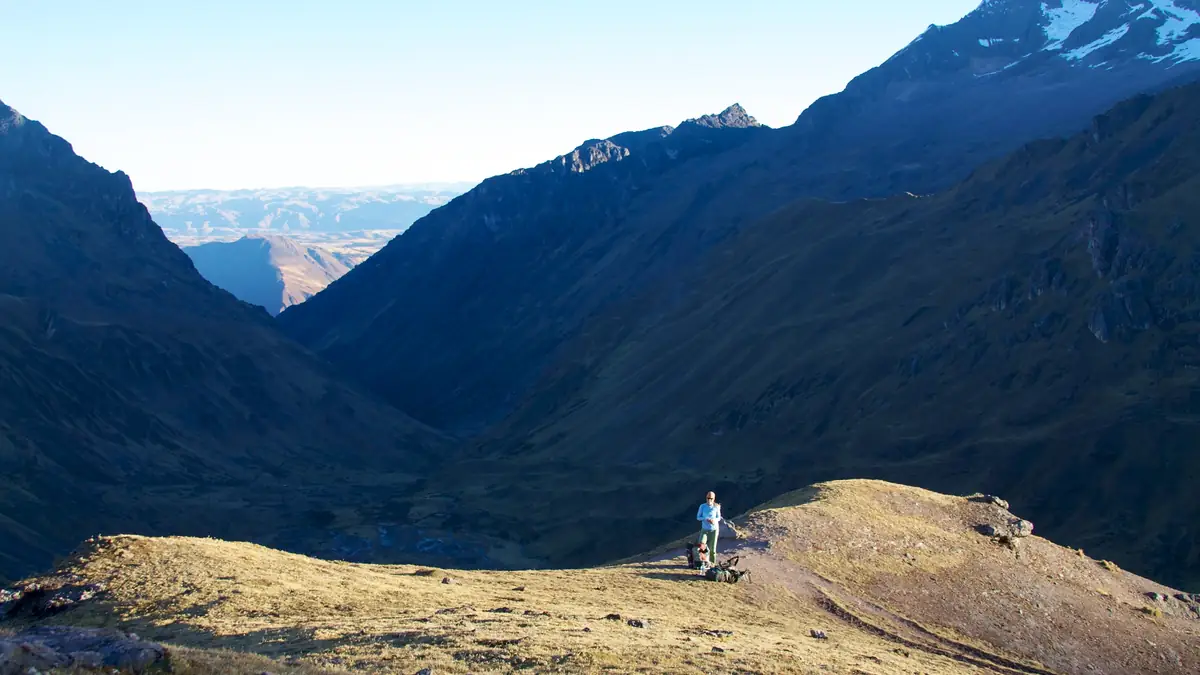 Hiker on a pass of the Lares route looking down the valley
