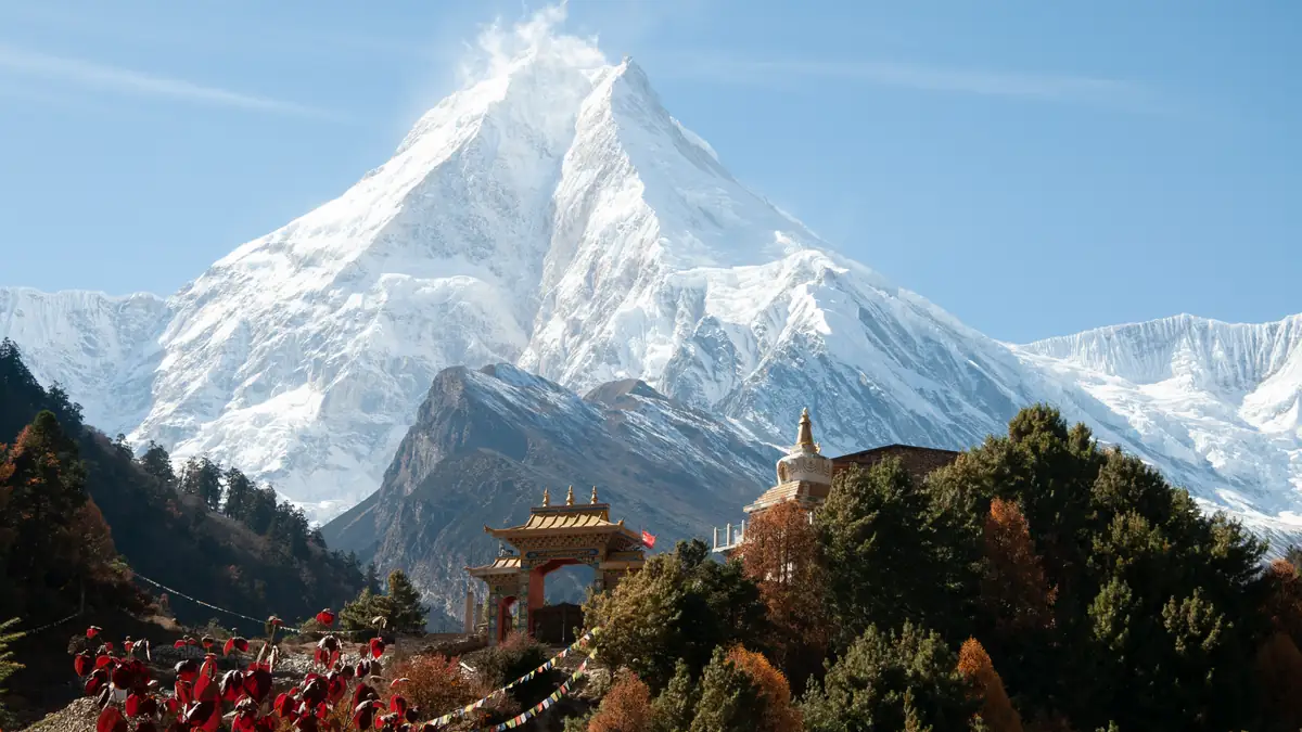 Das Tor des Klosters von Lho mit dem Manaslu dahinter, Mönche in roten Roben davor