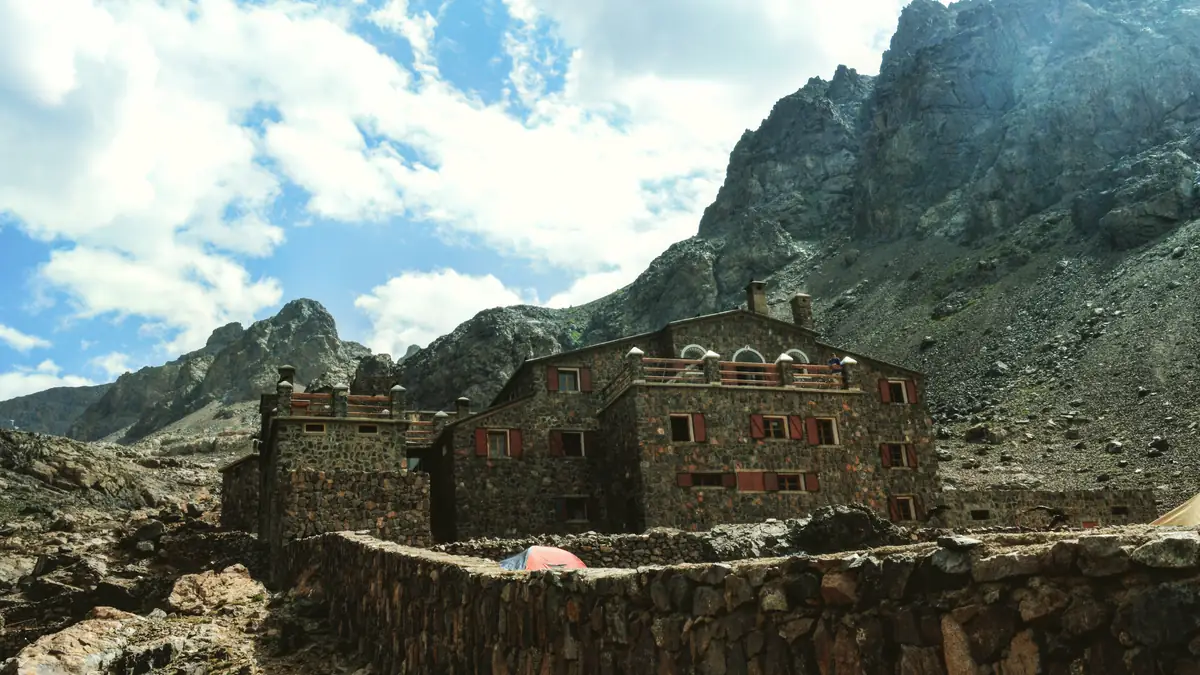 The stone building of the Refuge du Toubkal with tents in front