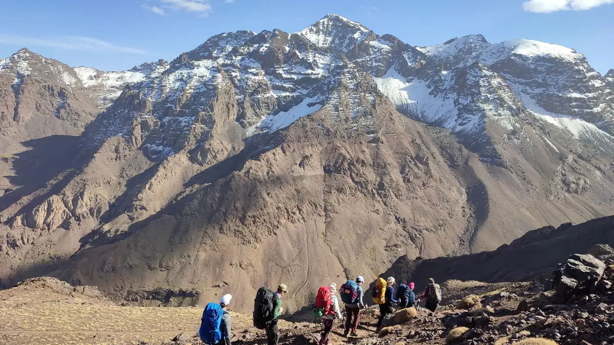 Group of hikers on the way to the Toubkal refuge, the snow-covered summit ridge behind