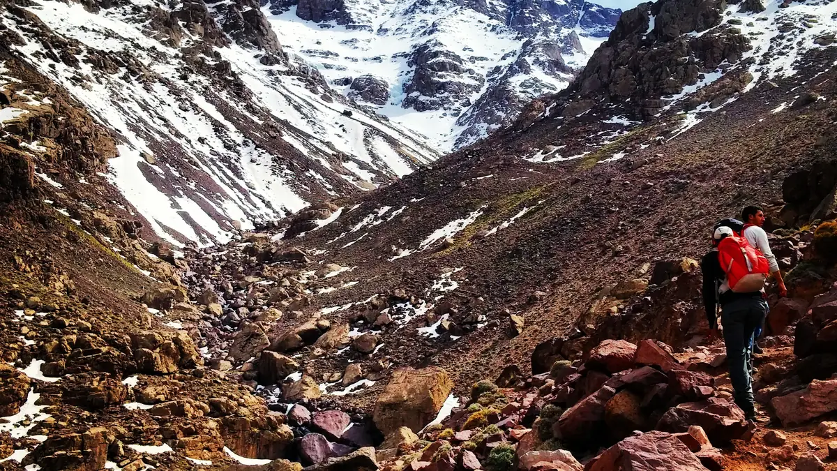Wanderer auf halbem Weg zum Gipfel im Schutt und Altschnee des Südkars